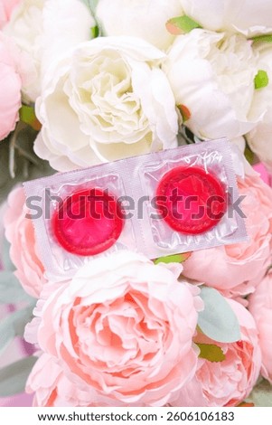 red condoms are lying on a background of pink peonies, space for text. High quality photo
