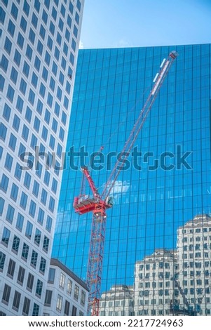 Red constructiion crane outside modern buildings in downtown Austin Texas. Urban city landscape with views of tall apartments, office units and construction machine.