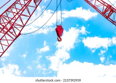 Red construction crane hook against sky
