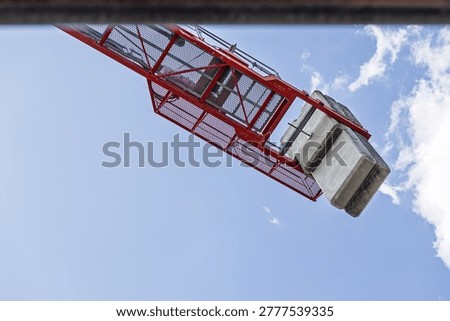 Red construction crane operating with concrete counterweights