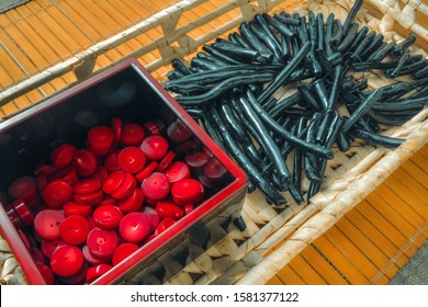 Red coral beads in small black box and black coral sticks on natural bamboo mat. Traditional bamboo pad with parts of coral beads