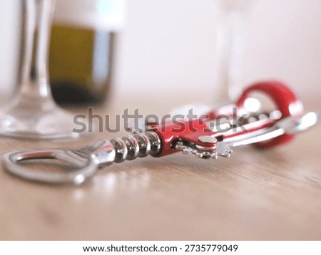 Red Corkscrew Resting On A Table Near Glass
