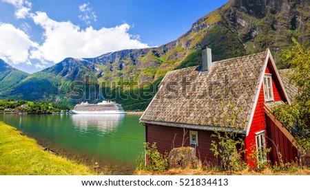 Red cottage against cruise ship in fjord, Flam, Norway