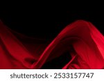 Red Cotton fabric flying in curve shape, Piece of textile Red cotton fabric throw fall in air. Black background isolated, dark shading environment