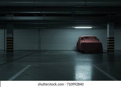     Red covered vintage car in empty underground parking background with copy space 