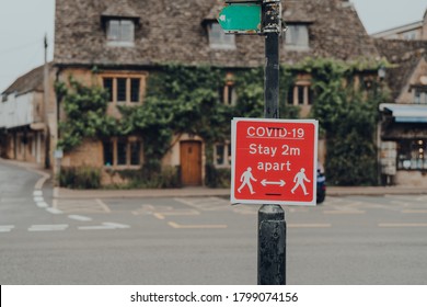 Red Covid-19 Stay 2 Metres Apart Warning Sign On A Street In Bourton-on-Water, Cotswolds, UK, During COVID 19 Pandemic. Selective Focus.