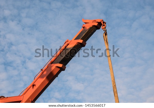 Red crane boom\
against the blue sky. Car manipulator unloads the pipe.\
Construction works. Summer. Sunny\
day.