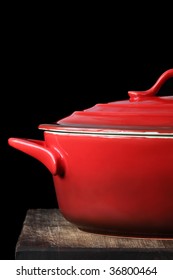 Red Crock Pot Or Casserole Dish, On Kitchen Board, Over Black Background.