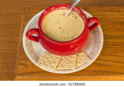 Red Crock Pot Full Of Chicken And Dumpling Soup With Saltine Crackers.  Rustic Wooden Background.