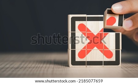 Red Cross mark, x, Wrong mark sign, Rejection sign in wooden cube hand stacking. Concept of negative decision making or choice of vote with copy space for background or text.