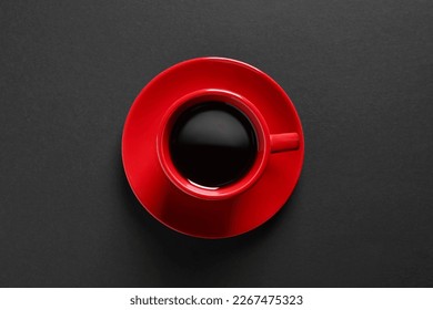 Red cup with aromatic coffee on black background, top view