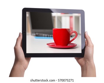 Red Cup Of Coffee Costs On The Office Desk On The Background Of Laptop And Shelves With Folders. Holding Tablet In Hands Isolated On White.