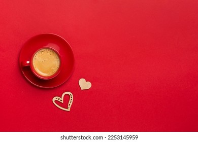 Red cup of coffee with hearts on color background, top view