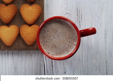 Red cup of hot cacao and heart shaped cookies on wooden background - Shutterstock ID 358055507
