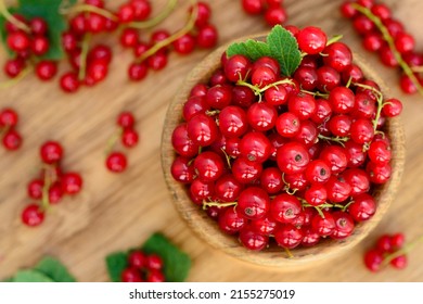 Red currant heap in a bowl. Currant red with leaf on wooden background. Organic currants with soft focus. Currant top view. 
