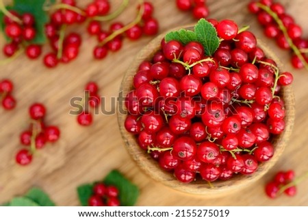 Red currant heap in a bowl. Currant red with leaf on wooden background. Organic currants with soft focus. Currant top view. 