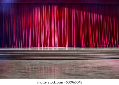 Red Curtains And The Stage Parquet With Stairs In Theater With Colorful Lighting.