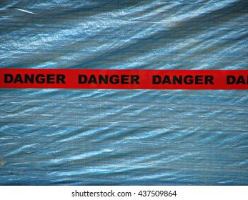 Red Danger Tape Over A Blue Wall Background