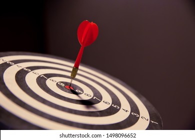 Red dart arrow  hitting in the target center of dartboard on bullseye for Business focus performance and skill concept.