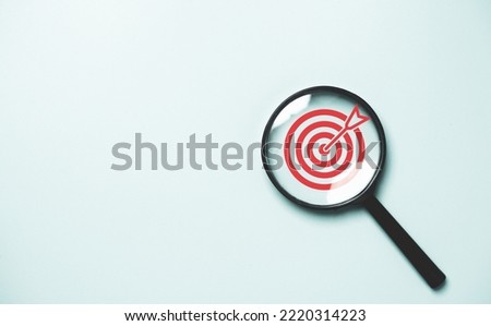 Red dartboard inside of black magnifier glass on blue background for setup objective target and business goal concept. 