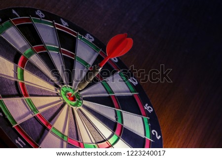 Red Darts arrow on the target center dartboard on wooden floor on the game focuses on success, planning to be smart concept on vintage tone