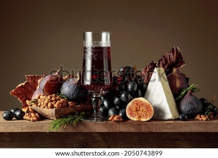 Red dessert wine with cheese brie and fruits on a wooden table. Copy space.