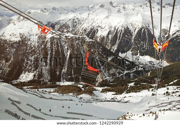 red detailed cable car lift way to snowy\
mountains with forest view at austria\
ischgl