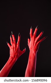 Red devil hands with sharp black nails, Halloween theme, studio shot on black background 