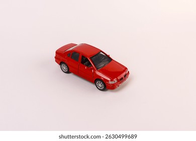 red die-cast toy car model placed on a seamless white-to-peach gradient surface, illuminated by soft directional lighting that accentuates the car’s vibrant paint finish, detailed door seams, silver