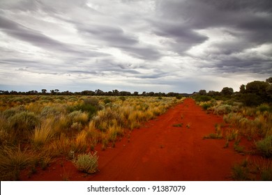 Red dirt outback road in Australia with a stormy sky.