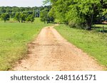 Red dirt road through a green pasture in April in central Alabama.