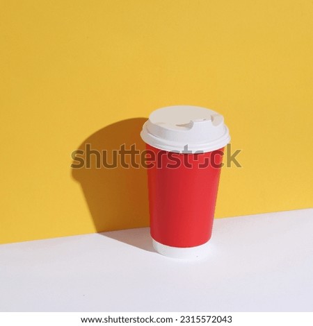 Red disposable cup on yellow-white background with shadow