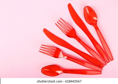 Red Disposable Cutlery Lie On A Pink Background