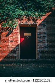 red door against brick wall with ivy and light shinning at 45 degree angle - Shutterstock ID 1122201182