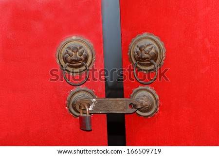 Red door knocker on the metal  