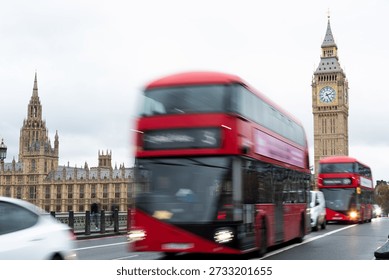 Red double decker buses moving through london westminster bridge. Rush hour traffic with motion blur, passing the houses of parliament Elizabeth tower and big ben