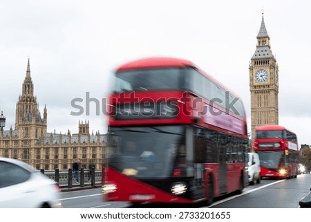 Red double decker buses moving through london westminster bridge. Rush hour traffic with motion blur, passing the houses of parliament Elizabeth tower and big ben