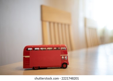 A Red Double-decker Bus On The Kitchen Table. A Bus With A Red Sticker On The Side, A Clean Place For Text. The Interior Of The Furniture In The Apartment. A Table With Chairs In The Background.