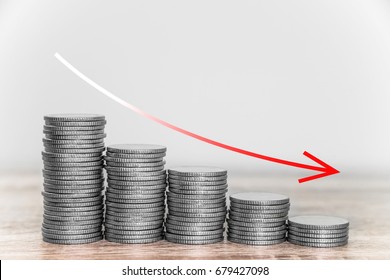 Red downward arrow with coins stacks background, Economic graphs with the curve down.