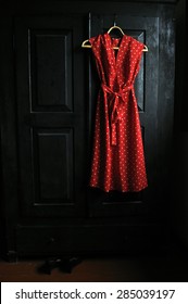 Red Dress In A White Dots  On A Wooden Hanger And  The Black Shoes On A Flooor