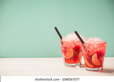 Red Drink With Ice. Cocktail Making Bar Tools, Raspberry, Lime, Oranges And Mint Leaves. Raspberry Mojito On Blue Background