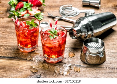 Red drink with ice. Cocktail making bar tools, strawberry and mint leaves