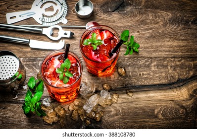 Red Drink With Ice, Mint Leaves And Strawberry. Cocktail, Campari, Aperol, Caipirinha, Mojito, Soda Water. Dark Toned Picture