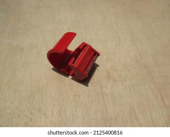 A Red Duct Tape Cutter With A Saw-like Serrated Blade.