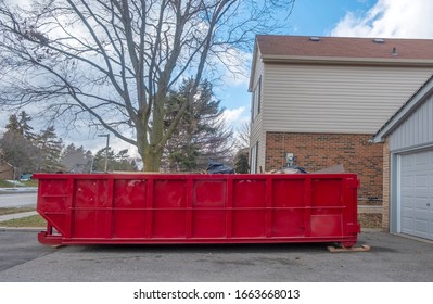 Red Dumpster Bin On The Driveway Of A Suburban House