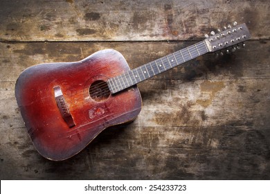 Red Dusty Guitar On A Wooden Table