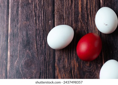 Red easter egg and white eggs on a wooden table