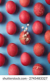Red Easter eggs float on blue background, one egg holds pussy willow with twine for minimal spring holiday greeting layout.