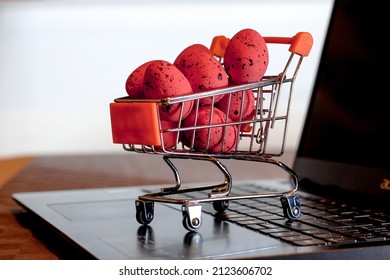 Red Easter eggs placed in supermarket shopping cart on a keyboard of laptop computer illustrating online shopping for holiday. - Powered by Shutterstock