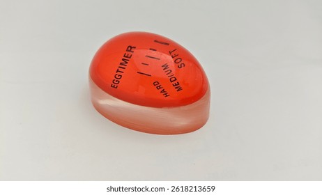 Red Egg Timer with Doneness Indicator. A close-up image of a red egg timer showing soft, medium, and hard levels. Ideal for precise egg boiling in kitchen settings.